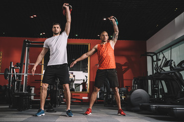 handsome trainer lifting weight together with african american athlele