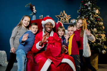 African Santa Claus and happy little children on the background of the Christmas tree