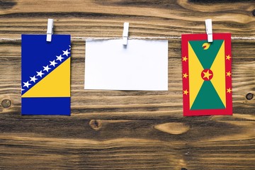 Hanging flags of Bosnia Herzegovina and Grenada attached to rope with clothes pins with copy space...