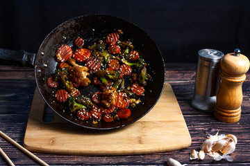 A hot pan with fried vegetables, broccoli, cauliflower, carrots.