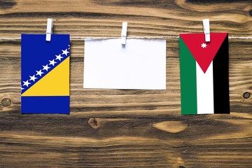 Hanging flags of Bosnia Herzegovina and Jordan attached to rope with clothes pins with copy space...