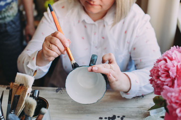 Woman working In her pottery studio. Ceramic workshop. Paint on clay cup in the pottery. Painting...