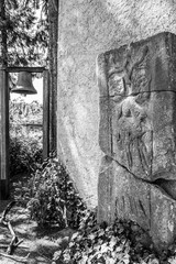 Old tombstone and a bell at the Monastery of St. Thomas, at Sankt Thomas, Germany, black and white photography