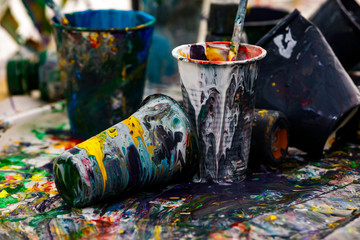 artist paintbrushes and acrylic colour in plastic cups close-up