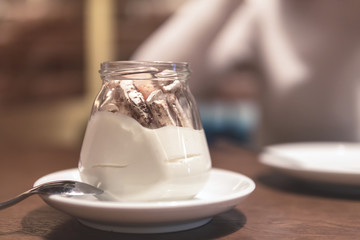 sweet cream dessert in a jar on a  wooden table in a cafe