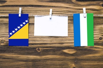 Hanging flags of Bosnia Herzegovina and Sierra Leone attached to rope with clothes pins with copy...