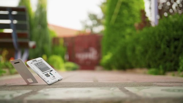 Mobile phone falls and breaks on the concrete ground in slow motion
