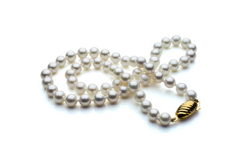 A single strand necklace of white pearls with a gold clasp are crossed over itself. Shown on a white background with shadow.