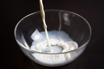  man pours milk into a glass Bowl to prepare pancakes. Also for drinking.