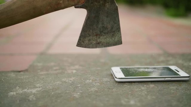 Mobile phone is crashed by axe on the concrete ground in slow motion