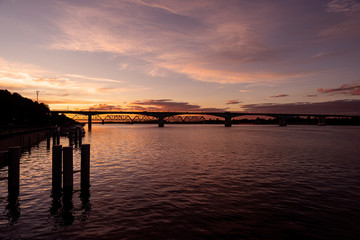 Obraz premium Russia, Golden Ring, Yaroslavl: Panorama view over Volga river water in the city center of the Russian town with colorful sunset, reflections and big bridges at the horizon - travel atmosphere