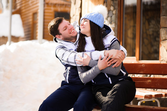 Happy couple in love hugging and kissing at winter resort