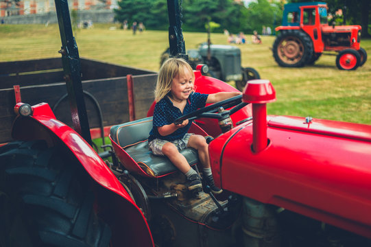 Little toddler pretending to drive old tractor