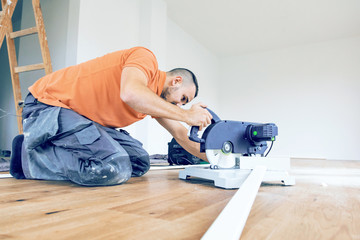 craftsman cuts wood plank with the chop saw on the construction