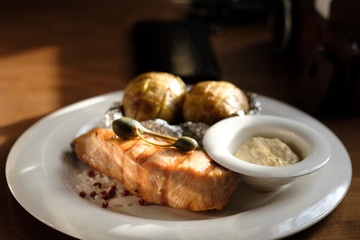 grilled salmon steak and baked potatoes with sauce