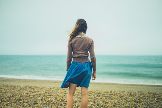 Young woman standing by the sea on a cloudy day