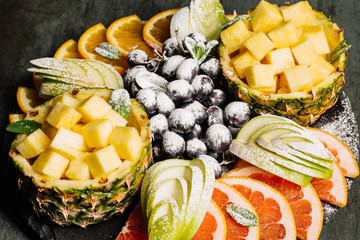 Fruit platter. Platter of grapefruit, pineapples, grapes and apples on a dark background