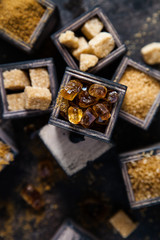 Flat lay composition with different types of sugar on dark background.