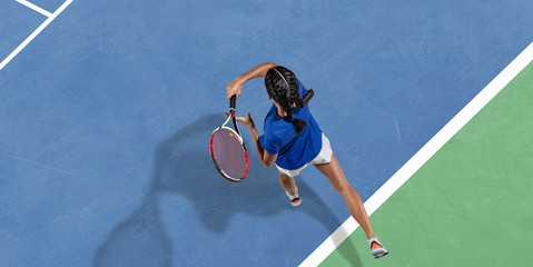 Young caucasian brunette woman in blue shirt playing tennis at the court. Hits ball with racket, outdoors. Youth, flexibility, power, energy. Copyspace. Top view. Motion, action, healthy lifestyle. - Powered by Adobe