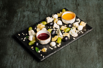 Cheese plate on a black table. Many kinds of cheese on a plate