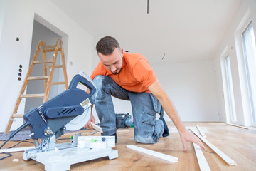 craftsman cuts wood plank with the chop saw on the construction