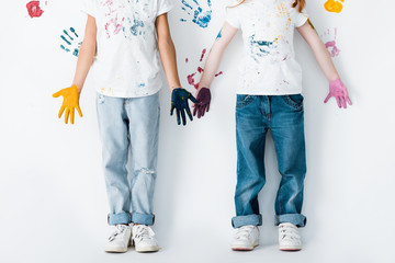 cropped view of kids in jeans with paint on hands standing near hand prints on white © LIGHTFIELD STUDIOS