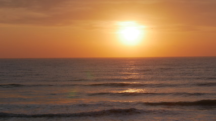 Sunrise over the sea. The sun is showing and coloring the sky in  red and golden yellow. Bright path to the shore.