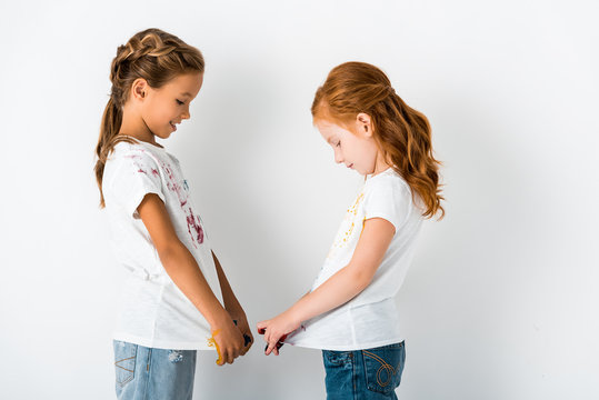 side view of cheerful kids with paint on t-shirts standing on white