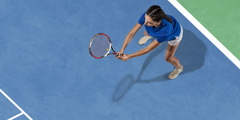 Fototapeta na wymiar Young caucasian brunette woman in blue shirt playing tennis at the court. Hits ball with racket, outdoors. Youth, flexibility, power, energy. Copyspace. Top view. Motion, action, healthy lifestyle.