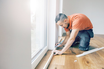 craftsman cuts wood plank with the chop saw on the construction