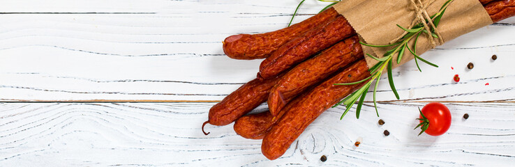 Kabanos or Cabanossi Thin Dry Smoked Polish Sausage on White Wooden Background. Selective focus.