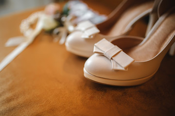 Wedding accessory bride. Stylish beige shoes, buttonhole and garter on wooden background.