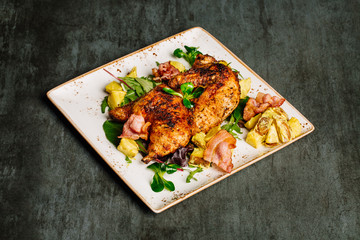 Grilled chicken with sauce on stone plate.