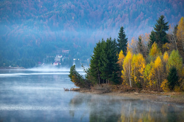 Naklejka na ściany i meble Lovely autumnal landscape with fog over the lake.