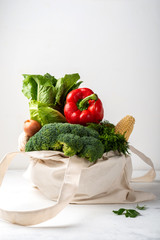 Grocery eco bag with different fresh vegetables on a light background. Zero waste purchases concept.