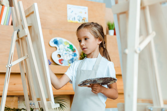selective focus of cute child painting in art school
