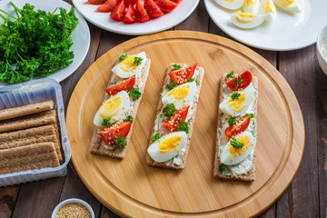 healthy crispbread open sandwiches with boiled eggs and fresh tomatoes cream cheese sesame seeds and ingredients