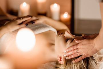 Beauty and youth. Hands of the masseuse make massage for a beautiful charming woman lying in a spa salon on a massage table.Traditional oriental massage therapy and beauty treatments.