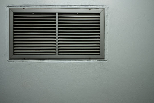 A grating of ventilation installed on the cement wall - Powered by Adobe