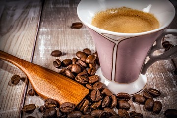 cup of coffee with spoon and beans on wooden table