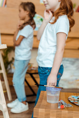 cropped view of kids standing near wooden table with gouache paints