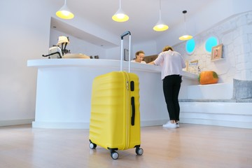 Yellow suitcase near reception desk in hotel lobby