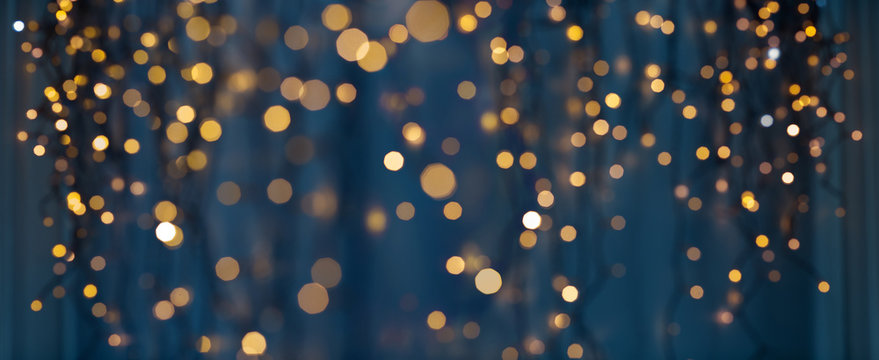 holiday illumination and decoration concept - christmas garland bokeh lights over dark blue background