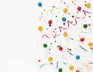  Festive composition with colorful confetti, Christmas ornaments and streamers on white. Celebration concept ideas for Christmas, New Year.