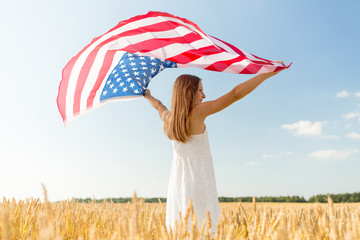 patriotism, independence day and country concept - happy smiling young girl holding national american flag waving over cereal field