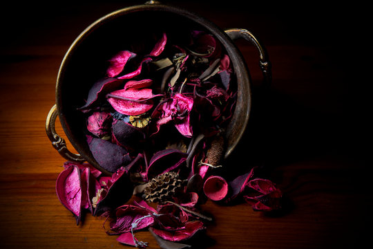 Petalos secos morados sobre tabla de madera y embase de laton