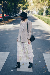 fashion blogger street style. fashionable woman posing wearing an oversized blazer, floral vintage dress, black ankle boots and a black trendy mini handbag. detail of a perfect fall 2019 outfit. 