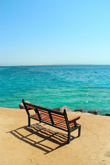 Empty bench near coastline at tropical resort. Exotic relaxation