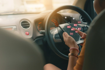 Woman looking at mobile phone while driving a car.Dangerous driver ,or  Young female driver using touch screen smartphone and gps navigation in a car.