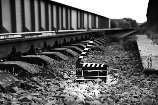 Black clapperboard with train tracks on background. Directing and filming cinema movie. Travel story.